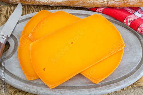 Fototapeta Naklejka Na Ścianę i Meble -  fromage orange en tranches sur une planche à découper