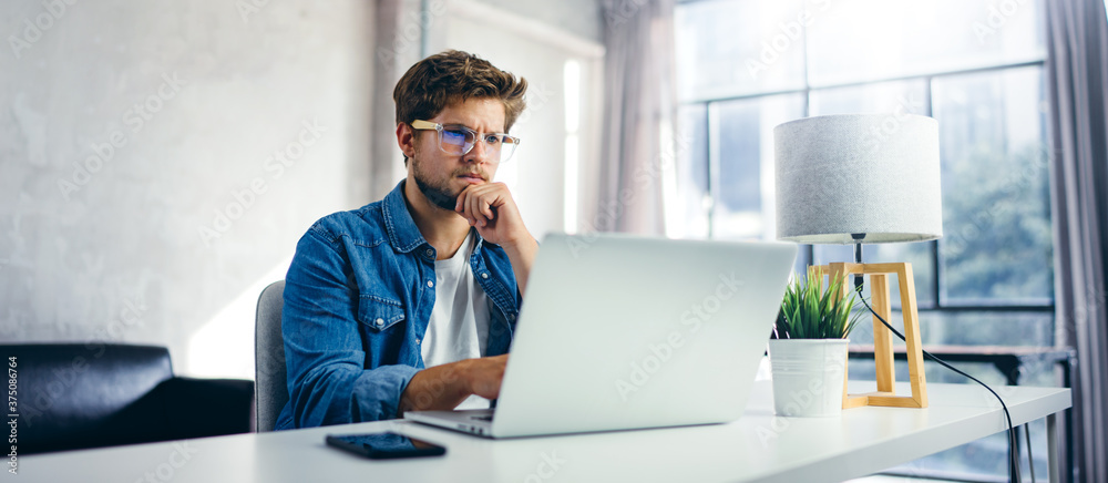 Man typing on laptop. Modern businessman at sunny office. Freelancer at work. Blogger or journalist writing new article Man typing on laptop. Modern businessman at sunny office. Freelancer at work. Blogger or journalist writing new article