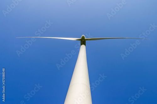 Wind turbine from below against a clear blue sky