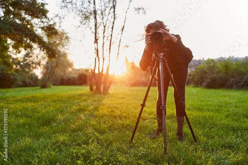 Frau als Landschaftsfotografin mit Kamera auf Stativ photo