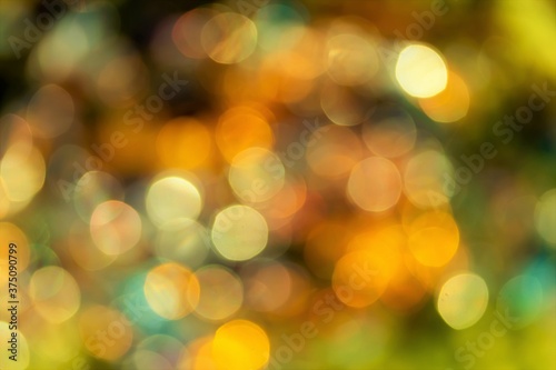Round bokeh, photo of festive lights out of focus, shades of yellow, blue, green, white.