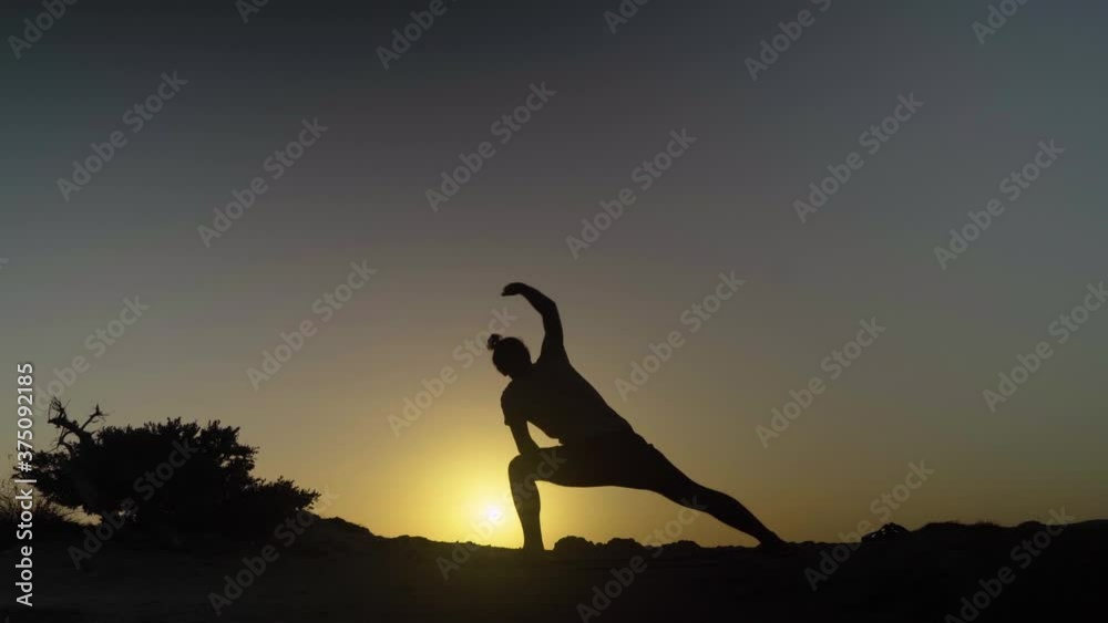 Silhouette Of A Man Practicing Yoga Positions in Nature at Sunset Silhouette Of A Man Practicing Yoga Positions in Nature at Sunset