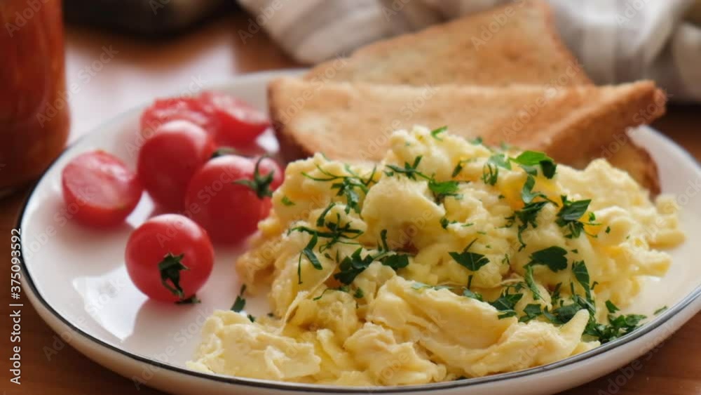 Scrambled eggs with tomatoes and toasts on plate, tasty breakfast served Scrambled eggs with tomatoes and toasts on plate, tasty breakfast served