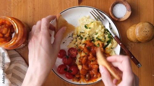 Scrambled eggs and baked beans breakfast. Woman eating omelette scrambled eggs with baked beans and toasts for breakfast, top view