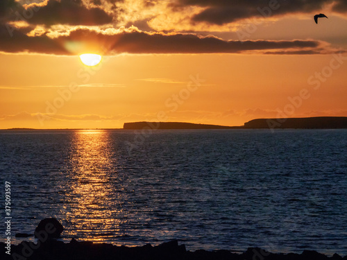 Sunset sky over ocean, Galway bay, Ireland, Warm orange and dark blue tones, Sun flare. Nobody.