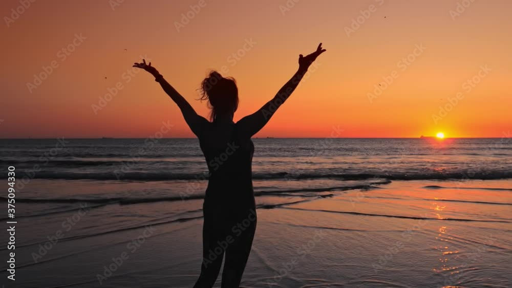 Silhouette of woman on the beach at sunset, golden sand and sun over the horizon Silhouette of woman on the beach at sunset, golden sand and sun over the horizon