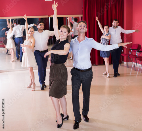 Adult dancing couples enjoying latin dances in modern studio