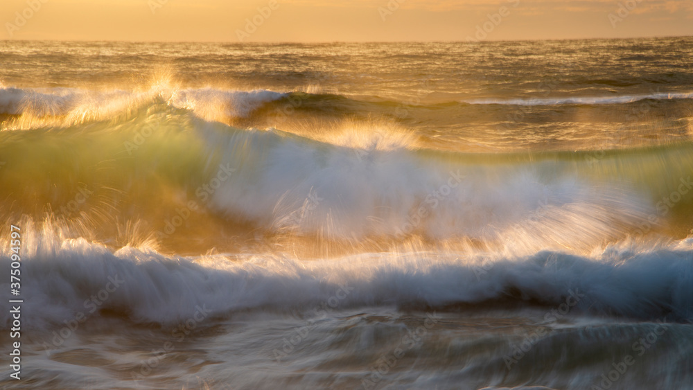 Crashing waves back lit by the setting sun. Image taken using slow shutter speed to capture the movement of the waves.