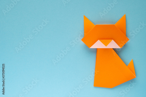 orange origami cat on sky blue background