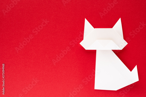white origami cat on red background