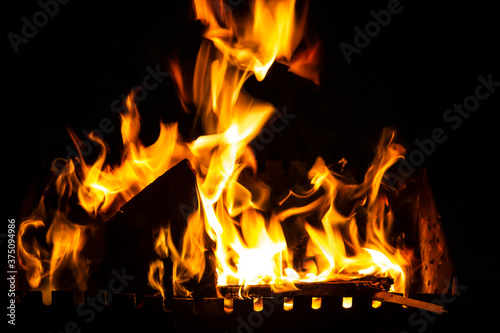 Fire on a dark background. Fire from firewood close up. Flaming burning sparks close-up, fire patterns. Red and orange Infernal glow of fire in the dark.