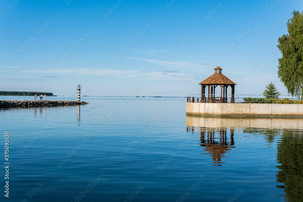 A little lighthouse and see on a sunny summer day, calm blue water and sky, bower, summerhouse, pavilion A little lighthouse and see on a sunny summer day, calm blue water and sky, bower, summerhouse, pavilion