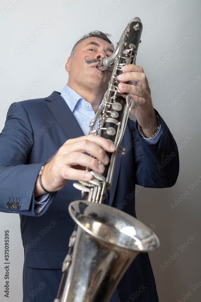 Fototapeta premium A man, dark, short hair, plays the bass clarinet. Studio, light background