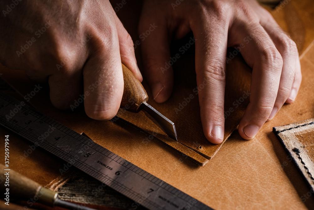 Close up of a shoemaker or artisan worker hands. Leather craft tools on old wood table. Leather craft workshop. Close up of a shoemaker or artisan worker hands. Leather craft tools on old wood table. Leather craft workshop.