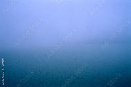Blue rippled surface or the artificial Paltinu Lake during a misty autumn day in the Doftana Valley in Romania