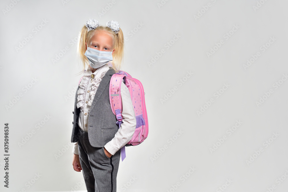 Schoolgirl 7 years old wearing a protective mask and with a school backpack, studio photography Schoolgirl 7 years old wearing a protective mask and with a school backpack, studio photography