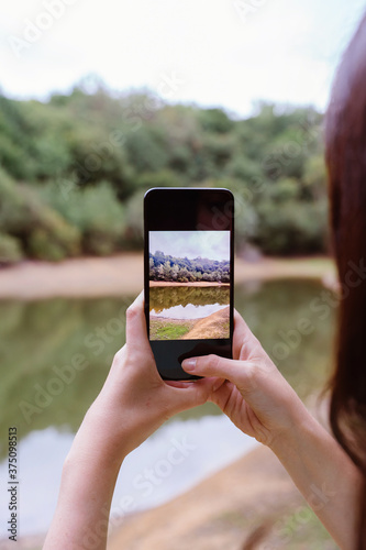 Unrecognizable woman taking a picture with phone to a travel destination in France.