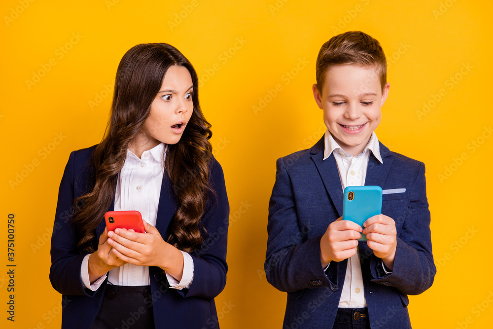 Portrait of his he her she attractive addicted cheery small little schoolkids using device browsing post smm blog girl peeking spy isolated bright vivid shine vibrant yellow color background Portrait of his he her she attractive addicted cheery small little schoolkids using device browsing post smm blog girl peeking spy isolated bright vivid shine vibrant yellow color background