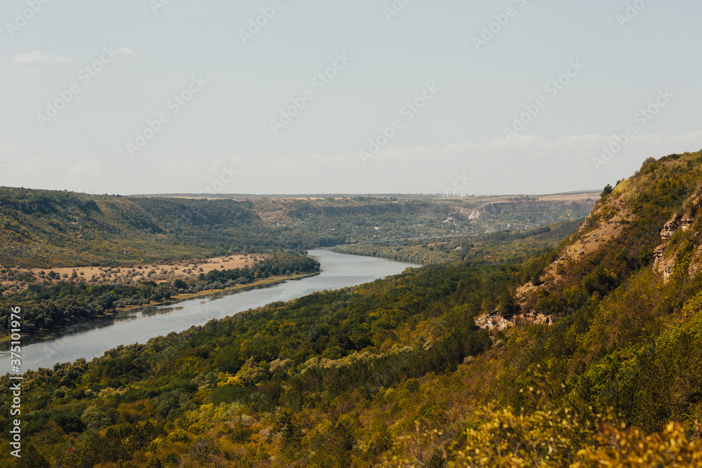 Panoramic photo of river, mountains and forest. River valley in the forest surrounded by mountains. 