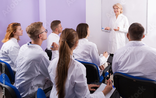 Elegant young female teacher lecturing to medical students at auditorium