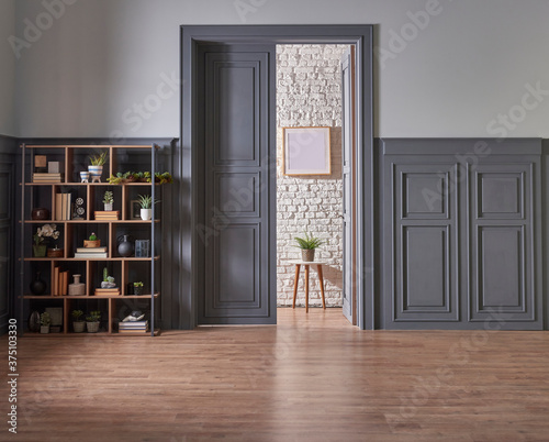 Decorative wooden bookshelf in the classic grey wall and door style, lamp frame and vase of green plant.