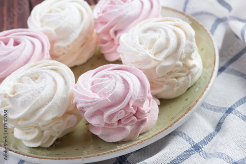 Pink and white meringue cookies on green plate