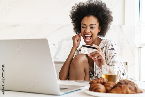 Excited young woman holding credit card