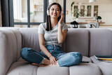 Image of woman listening music with headphones while sitting on sofa