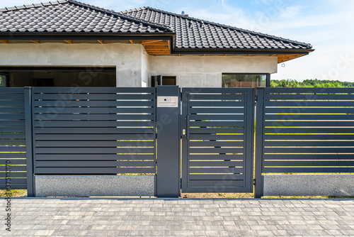 Fotografia Modern panel fencing in anthacite color, visible wicket with videophone and a house in the background