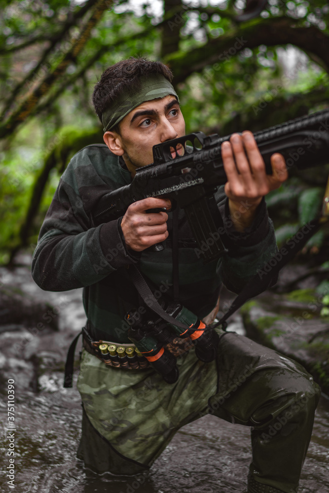 Inside the stream, soldier or revolutionary member or hunter in camouflage, gun in his hand, hunting concept