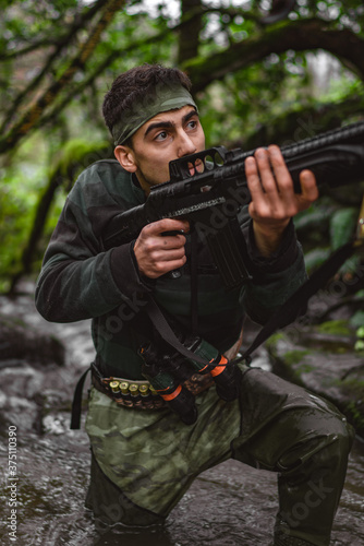 Inside the stream, soldier or revolutionary member or hunter in camouflage, gun in his hand, hunting concept