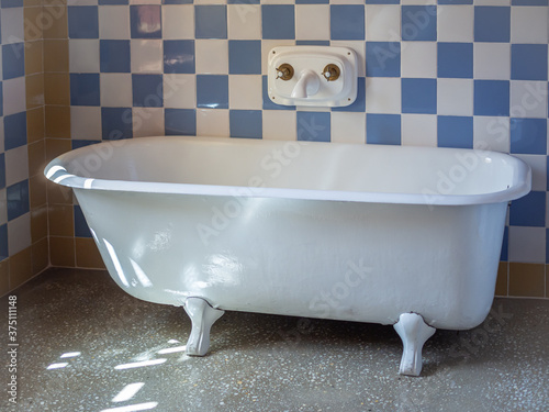 Vintage bathtub in the vintage bathroom with blue and white tile walls