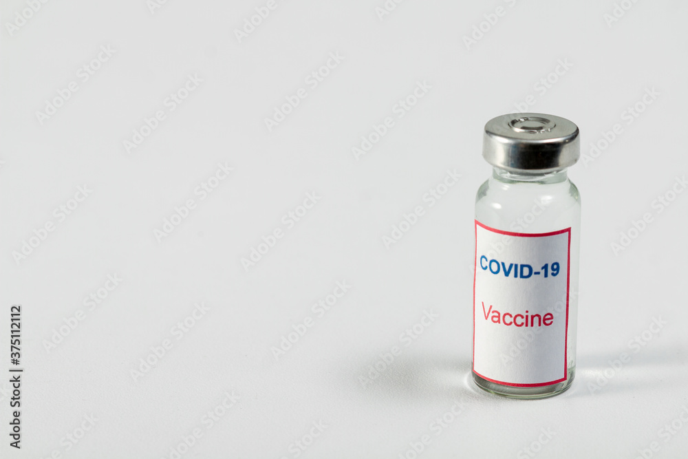 A bottle with a COVID-19 medicine Vaccine stands on the right against a light background. There is a place for an inscription on the left. A bottle with a COVID-19 medicine Vaccine stands on the right against a light background. There is a place for an inscription on the left.