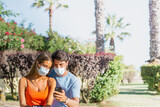 Beautiful couple with surgical mask reading health alerts on their smartphone