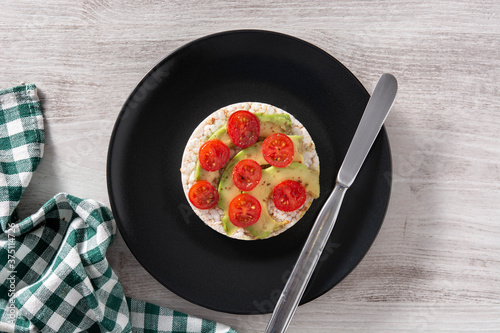 Puffed rice cake with tomato and avocado on white wooden table