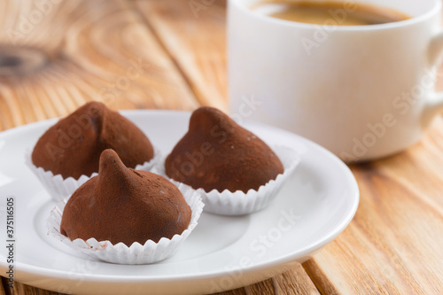 Chocolate truffles sweets in plate on wooden table