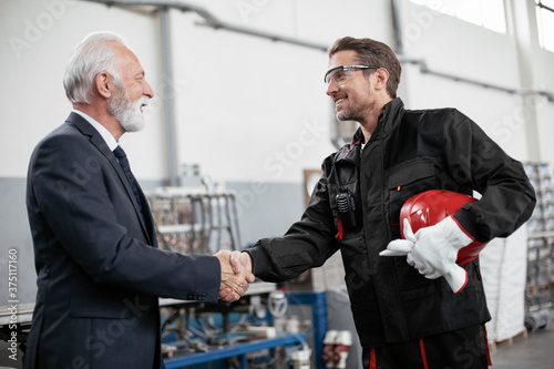 Colleagues working together. Arhitect and worker handshake in factory.