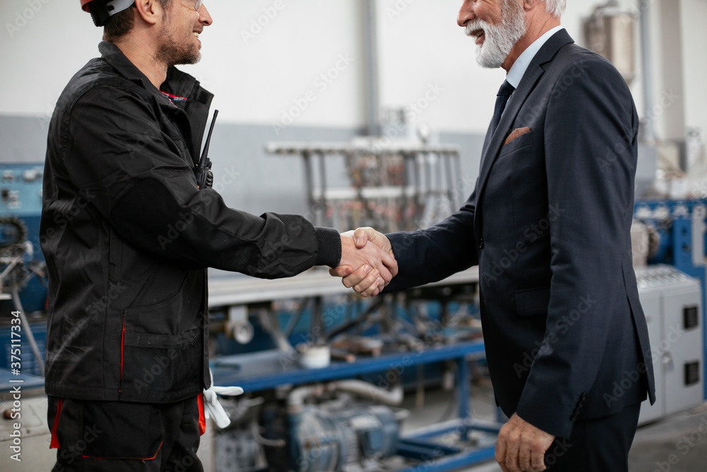 Colleagues working together. Arhitect and worker handshake in factory.