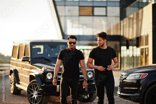 Two asian brothers man wear on all black posed near suv cars. © AS Photo Family