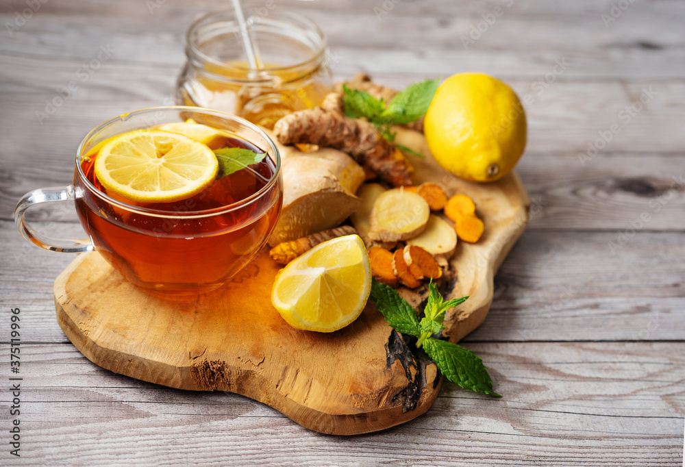 Ginger turmeric cup of tea on wooden board with ingredients Ginger turmeric cup of tea on wooden board with ingredients