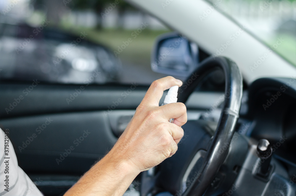 Man sanitizing wheel and salon of his car. Male hand holding sanitizer closeup Man sanitizing wheel and salon of his car. Male hand holding sanitizer closeup