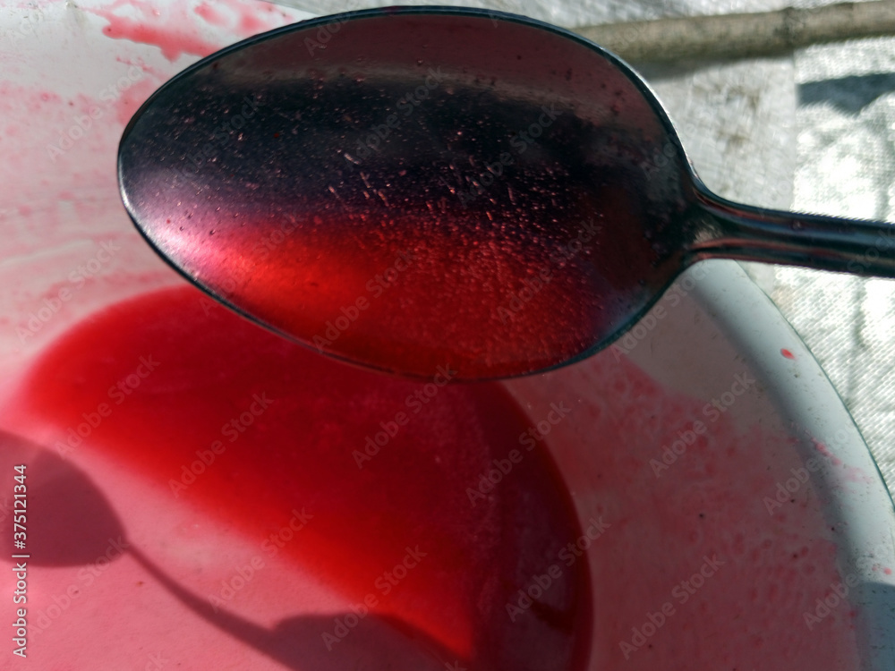 Photo of red jelly and bubbles texture. Red currant jam. Spoon full of jam. Blurry texture