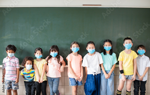 Group of diverse young students wear mask and standing together in classroom