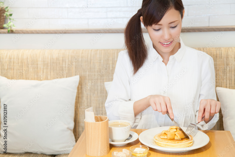 カフェでパンケーキを食べる女性