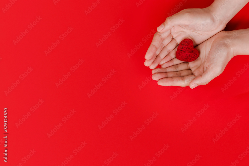 Women hands holding red heart on red background, top view with space for text. world heart day concept Women hands holding red heart on red background, top view with space for text. world heart day concept