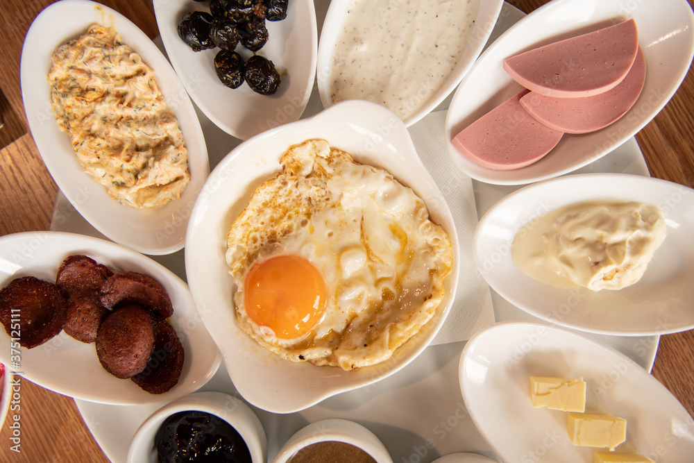 Flat lay view of served breakfast with fried eggs, salad, sauces, butter and jam Flat lay view of served breakfast with fried eggs, salad, sauces, butter and jam