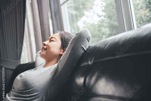 Happy woman relaxing on a sofa after work in the living room at home. © oatawa