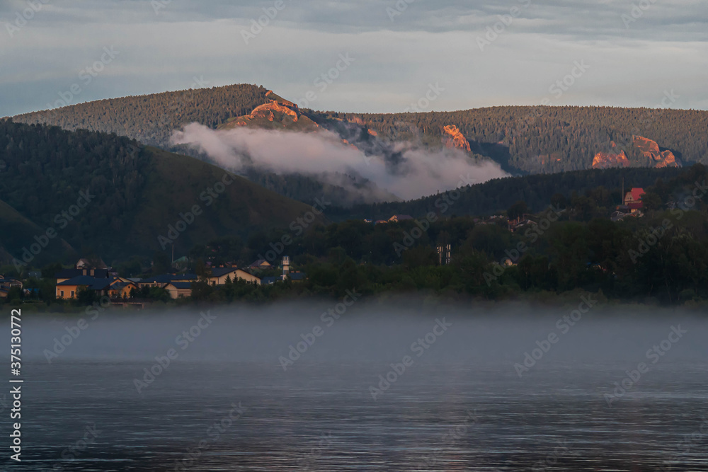 beautiful white fog rises in the evening over the mountains and over the river