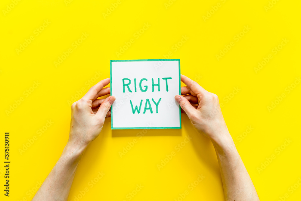 Business desicion. Right way icon in hand on yellow desk top view Business desicion. Right way icon in hand on yellow desk top view