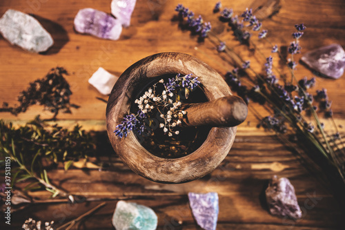 Pulverizing healing herbs and flowers with the mortar, esoteric ingredients for a therapy photo